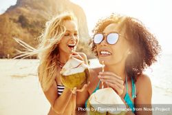 Two Women Talking And Laughing While Drinking A Tropical Cocktail