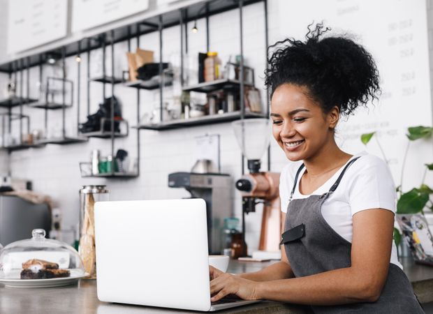 Woman smiling standing at laptop in coffeeshop