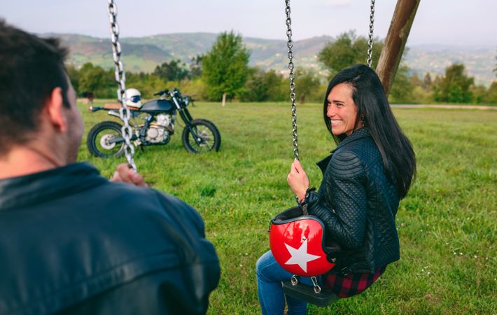 Happy young woman looking at her boyfriend sitting on a swing