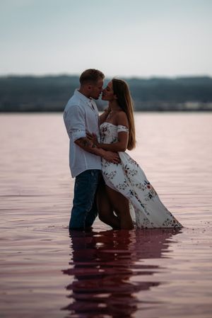 Side view of adorable couple embracing into an amazing beach with pink water