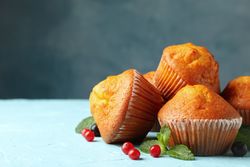 Composition with muffins and berries on blue background, close up