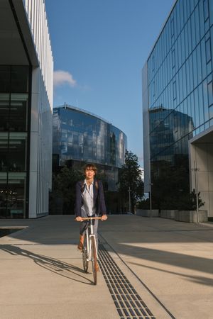 Cheerful businesswoman riding bicycle on street