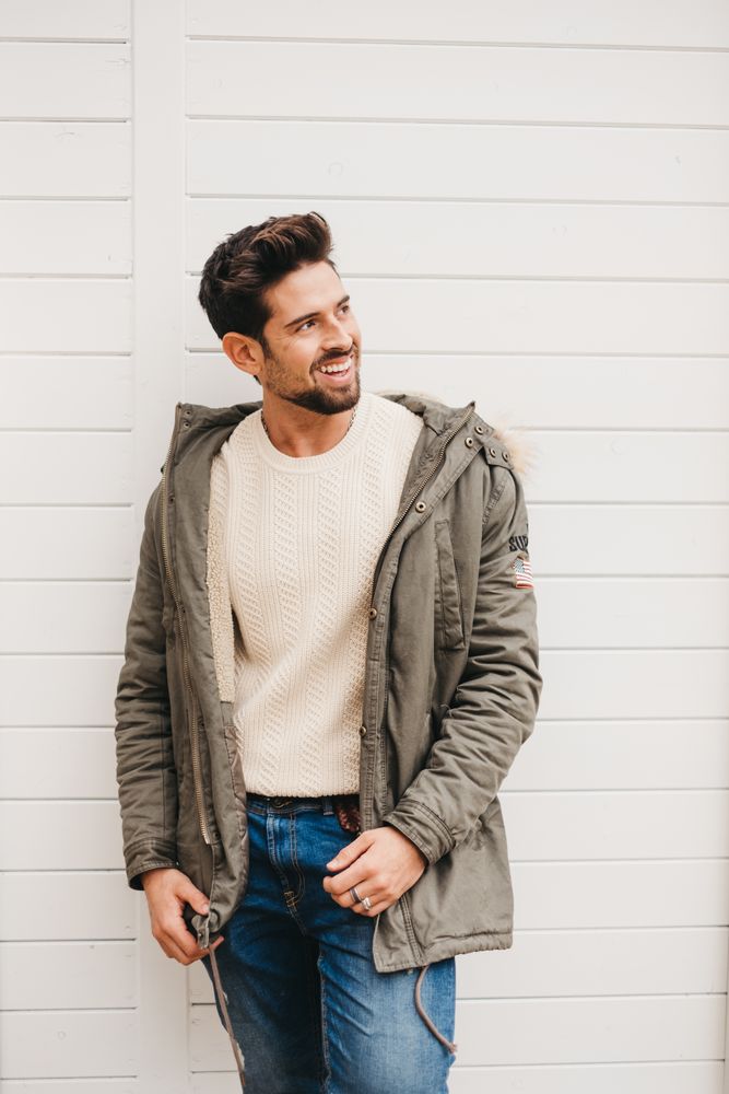 Cheerful stylish male standing against wooden wall