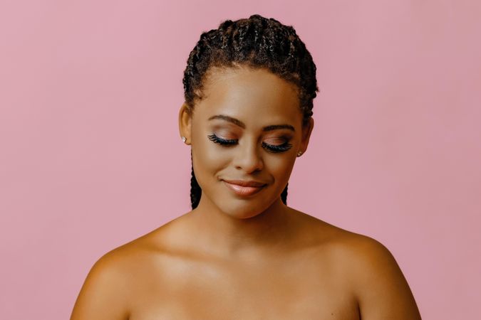 Black woman looking down in pink studio shoot