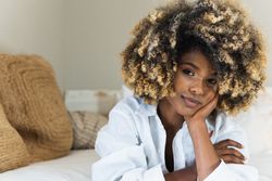 Thoughtful Black woman lying on bed in bedroom