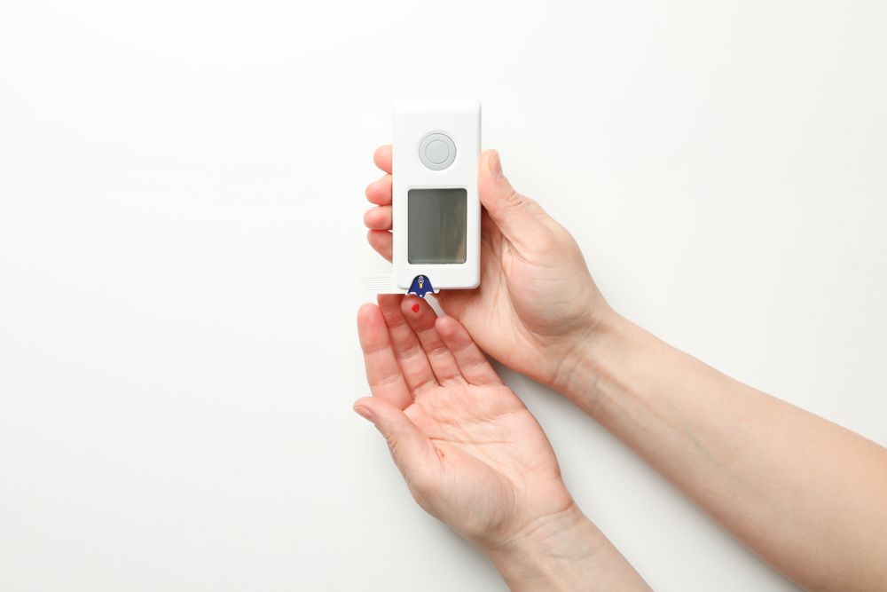 Female checking blood sugar level on blank background