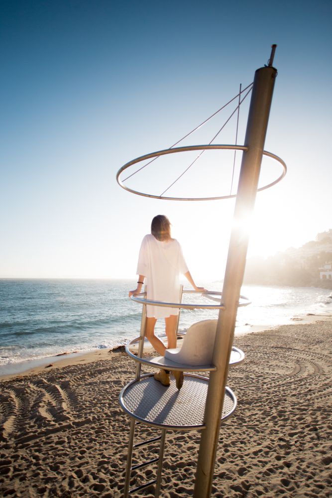 Beautiful blonde model standing on guard tower overlooking the beach