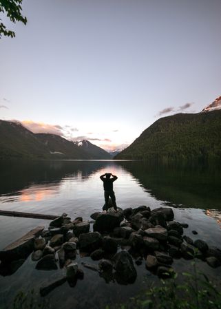 Person standing on rocks near lake