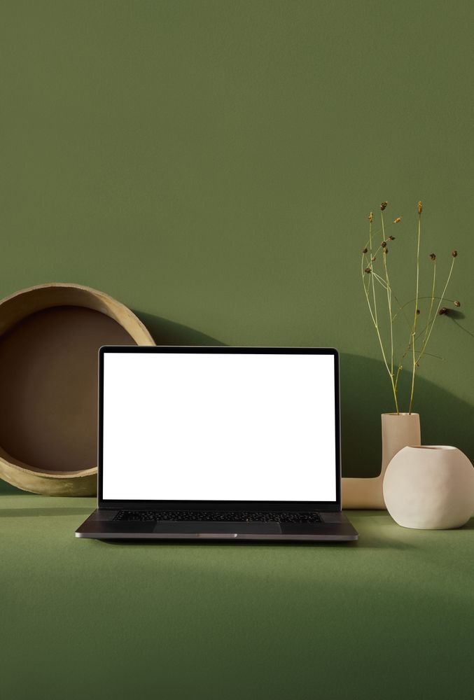 Laptop with blank screen on green desk