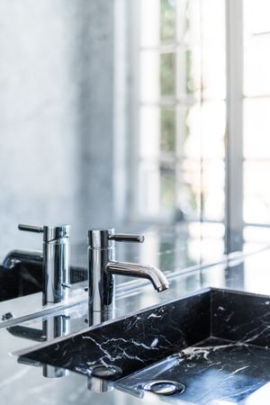 Marble sink and water tap in contemporary washroom