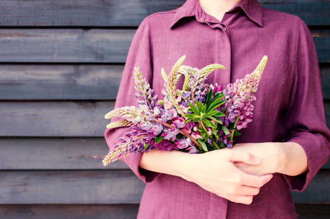 Woman in purple shirt holding a matching bouquet of flowers