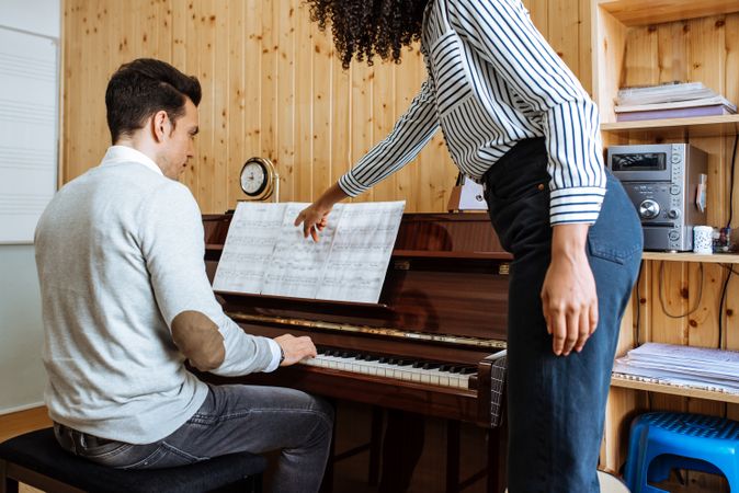 Man playing piano near woman teaching in studio