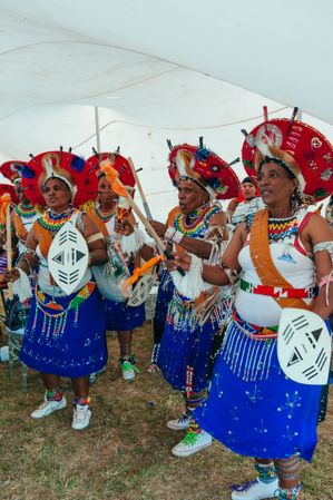 Group of elder women wearing traditional Zulu beaded jewelry and headdresses gathered together