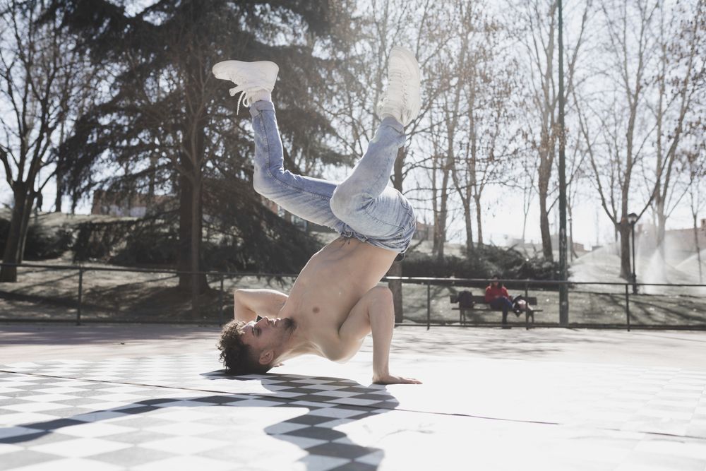 Shirtless man dancing break dance in park