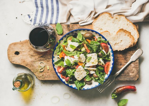 Greek salad with feta, tomatoes, and red wine on wooden board, horizontal composition