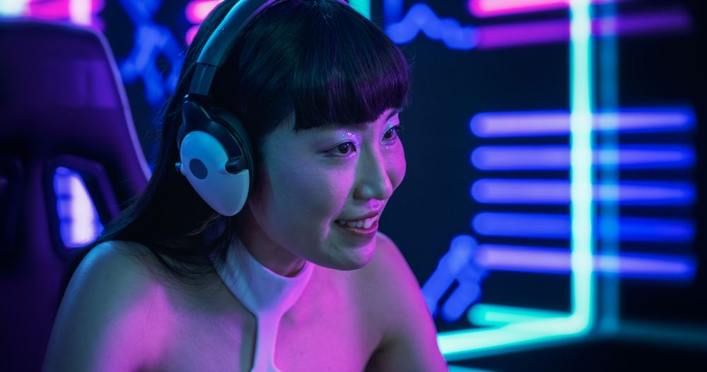 Portrait of a Japanese Young Female Wearing Headphones, Talking with Friends Online on a Computer.