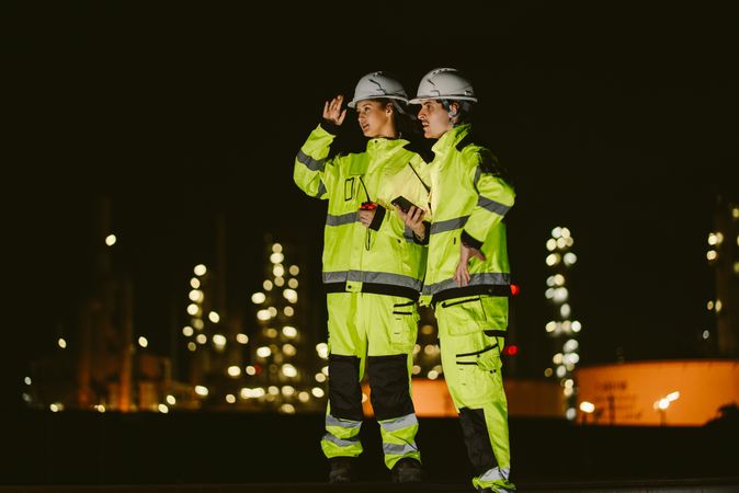 Two industrial workers observing and discussing at refinery factory