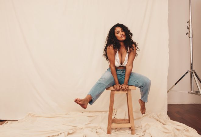 Body positive young woman looking at the camera with confidence sitting on a wooden chair