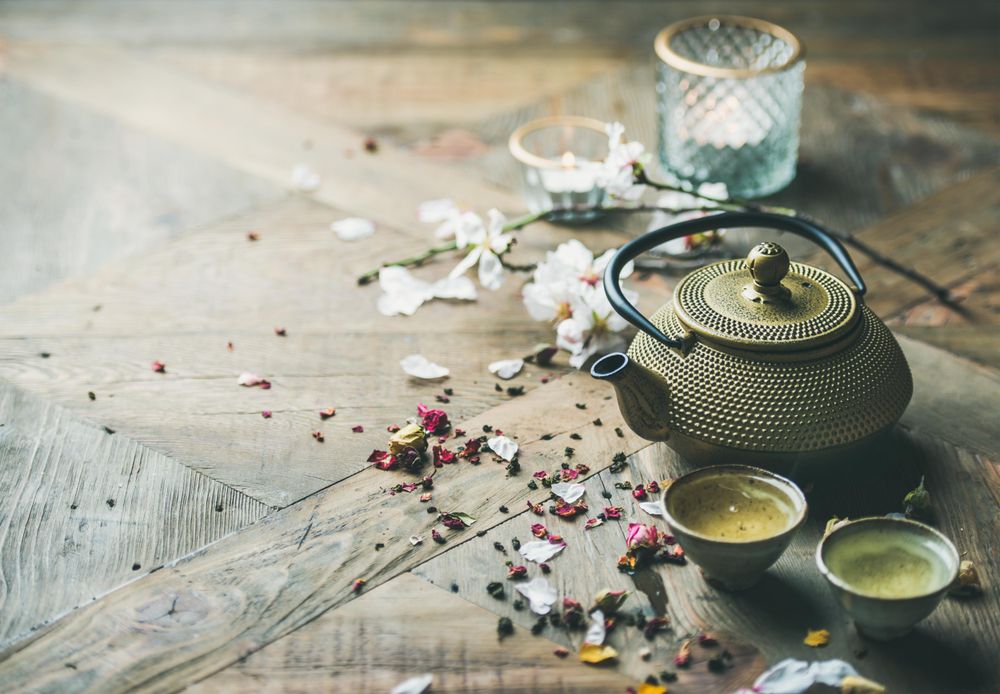 Golden teapot with little teacups on wood table