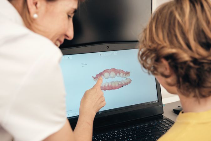 Dentist showing 3D teeth scan to faceless boy