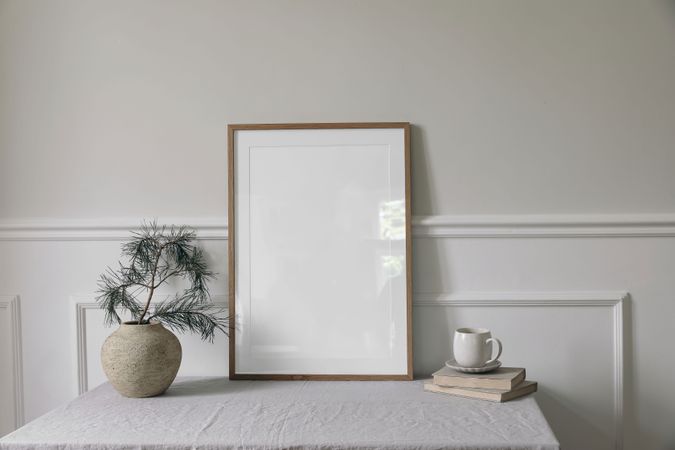 Blank vertical wooden picture frame mockup, cup of coffee on table