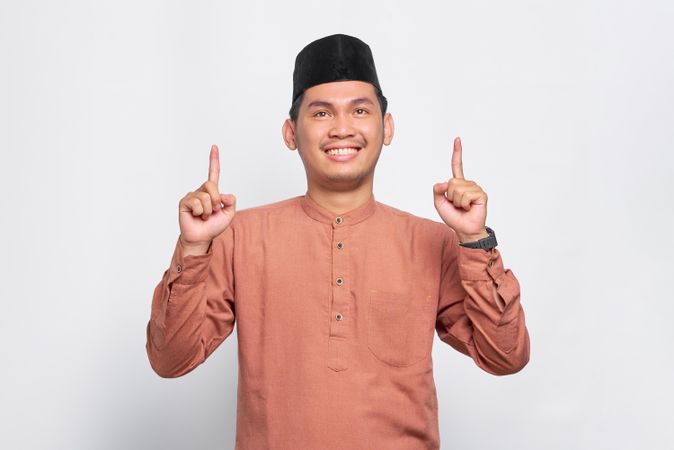 Muslim man in kufi head wear pointing up