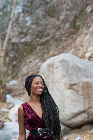 Happy woman with long braids wearing a red velvet jumpsuit