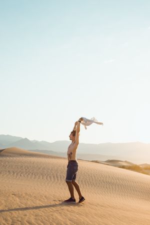 Side view of active young man without shirt enjoying wind in dry Death Valley