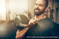 Man smiling while holding kettlebell to chest 4ZdpO0