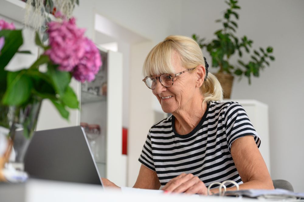 Happy mature woman using laptop in living room at home