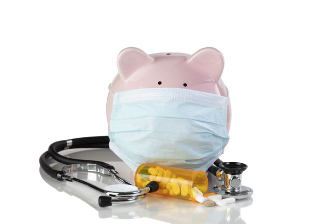 Piggy bank wearing surgical mask with medical drug supplies