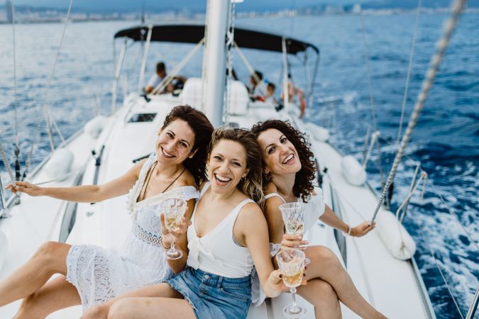 Cheerful friend with wine having fun on yacht