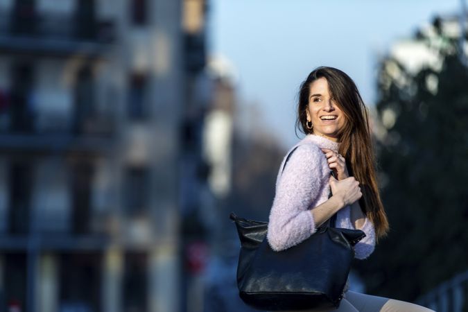 Happy woman with handbag outside at dusk