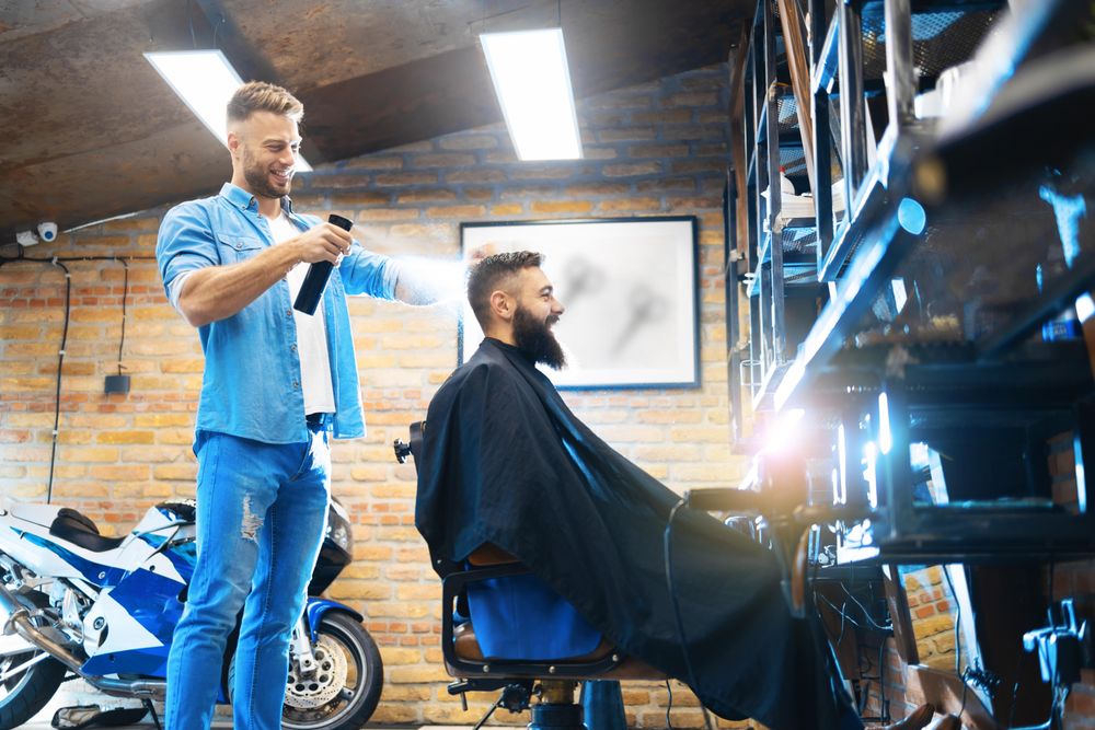 Smiling barber using hairspray on client