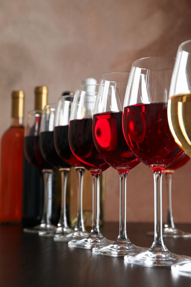 Bottles and glasses with wine on dark table, close up