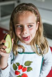 Girl with avocado licking lips