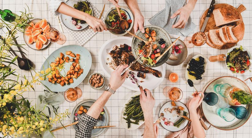 Flat-lay of peoples hands serving themselves dinner