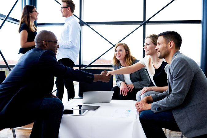 Male and female business associates shaking hands at an informal meeting in an office