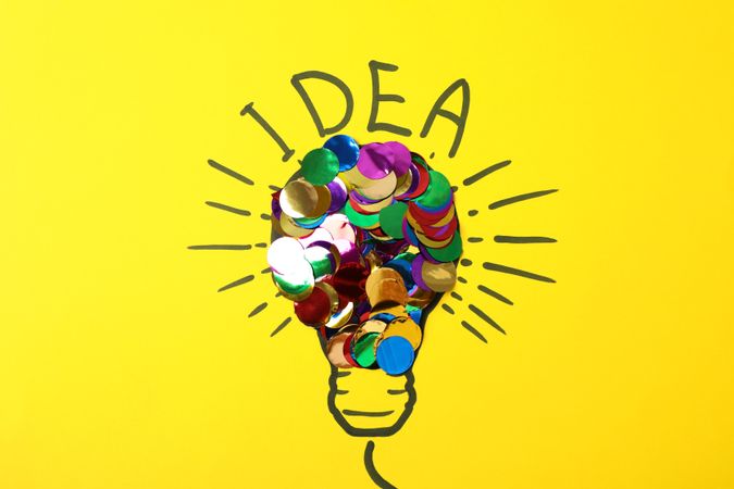 Drawn light bulb and multicolor glitter on yellow background. Good idea concept
