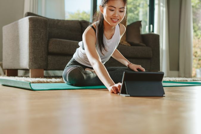 Woman using digital tablet while exercising at home