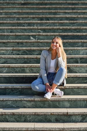 Smiling woman sitting on steps in contemplation