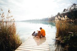 Man and woman lounging on a lakeside pier
