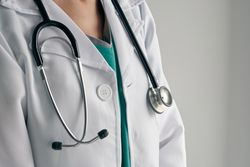 Faceless physician in medical robe with stethoscope