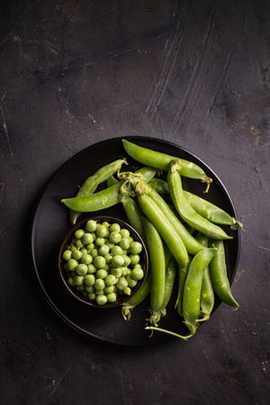 Fresh peas and pea pods on dark background