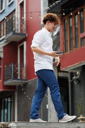 Asian man holding mobile phone walking in the city