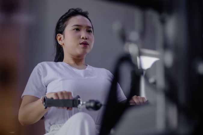 Dedicated Female Athlete Engages in Rowing Machine Workout Routine