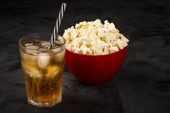 Bowl with salted popcorn and soda on the table.