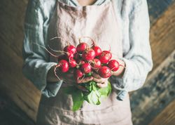 Woman holding bunch of root vegetables in her hands
