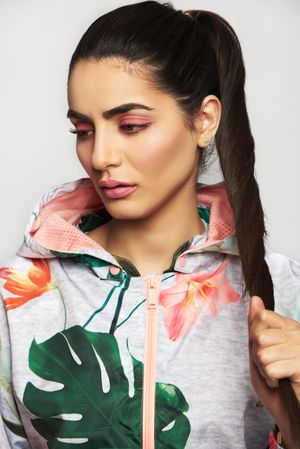 Beautiful woman pictured in colorful printed floral hoodie holding her long brunette pony tail