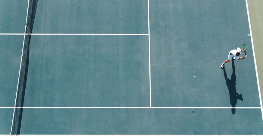 Aerial view of young tennis player playing on hard court